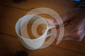 Close-up coffee in my hand , Hand of woman hold a cup of coffee on wood table