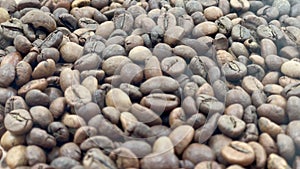 Close-up of coffee seeds. Roasted aromatic coffee beans with smoke emanating from the beans. Industrially prepared hot