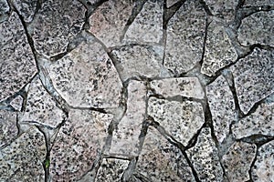 Close up of a cold and wet stone path. Stone walk texture, background with cracked stone material. Abstract ancient dark granite