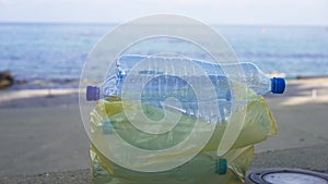 Close-up collected plastic bottles with beautiful Mediterranean sea waves rolling on coast at background. Concept of