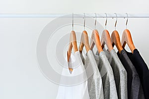 Collection of black, gray and white color hanging on wooden clothes hanger in closet or clothing rack photo