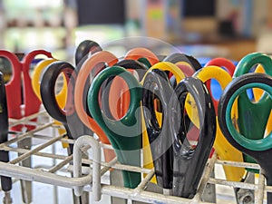 A close up of a collection of classroom scissors handles in a rack