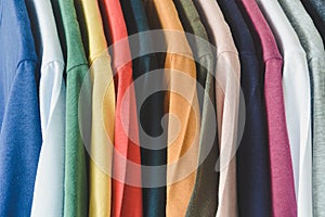 Close up collection of colorful t-shirts hanging on clothes hanger in closet or clothing rack