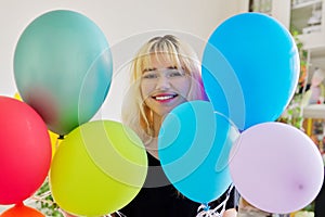 Close up of colored balloons and happy smiling face of blonde teen female
