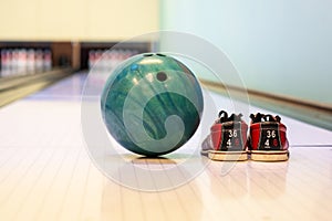 Close-up colorful bowling balls and bowling pins and bowling shoes on the bowling track.