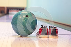 Close-up colorful bowling balls and bowling pins and bowling shoes on the bowling track.