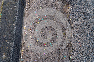 Close-up of colorful confetti on dirty street after a carnival parade has passed.