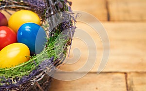 Close up of colorful Easter eggs in basket on wooden table.