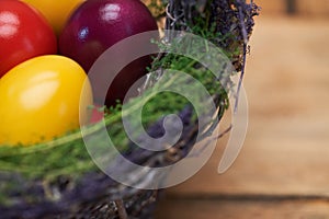 Close up of colorful easter eggs in basket on wooden table.