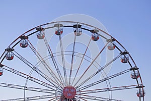 Close-up colorful Ferris wheel against blue sky. Abstract futuristic urban architecture, motion blur, selective focus.