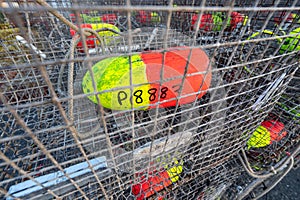 Close-up of a colorful float inside an empty crab or lobster pot stacked in a pile near the coast