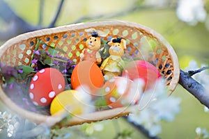 Close-up of colorful hand made Easter eggs and little bunnies figurines in a basket outdoors