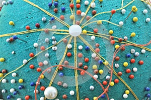 Close up colorful head of a pin and threads in pincushion