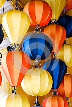 Close-up of colorful hot air balloon lanterns hanging against a yellow wall, creating a festive atmosphere