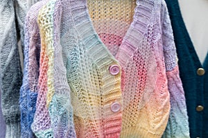 Close up of colorful knitted sweaters with buttons. Bunch of clothes of different colors for sale.