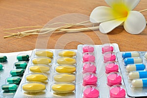 Close up colorful of medicine tablets and capsules with white flower and dried tree branch