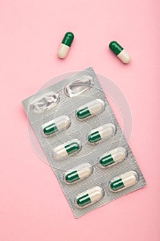 Close up of colorful pills on pink. Two-tone drugs and supplements. Capsules to be swallowed wrapped in the blister. Two tablets