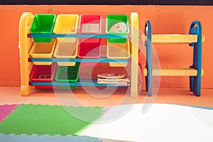Close up colorful plastic shelf and toy boxs in kids room with orange color background in vintage style.