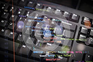 Close-up of colorful programming code overlay on black keyboard, representing modern software development, coding, and digital