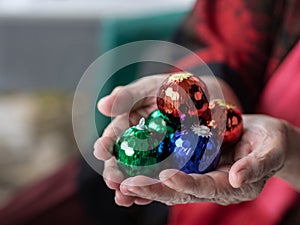 Close-up of colorful small balls in the hands of a senior woman indoor. Space for text. Concept of festival and holiday
