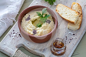 A close-up of a colorful snack composition on a wooden background. Delicious hummus in glass bowl and on a wooden plate.