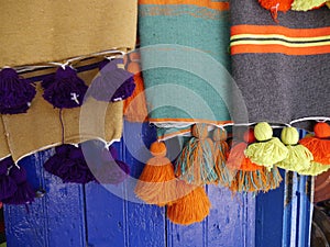 Close up of colourful, handmade Moroccan throws with tassels on sale