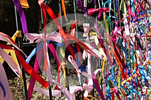 Close up of colourful strings of ribbon tied to a fence.  The background is intentionally out of focus or blurred