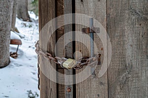 Close up of combination padlock and rusty chain on old wooden bathroom door