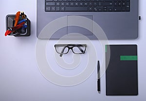 Close-up of comfortable working place in office with laptop, notebook, glasses, pen and other equipment laying on table