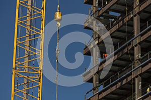 Close up of commercial office building under construction with construction worker ,crane, steel beams with weight of steel beams