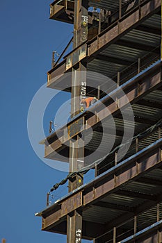 Close up of commercial office building under construction with construction workers ,steel beams with weight of steel beams sprypa