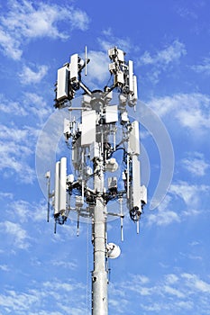 Close up of communications tower with blue sky and while clouds