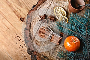 Close-up composition cinnamon sticks tied and dried lemon slices, anise star, branch of a blue fir tree, on wooden background