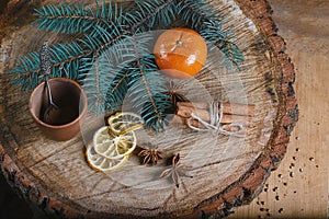 Close-up composition cinnamon sticks tied and dried lemon slices, anise star, tangerine, branch of a blue fir tree, on wooden back