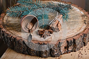 Close-up composition cinnamon sticks tied and ground cinnamon in a cup, anise star, branch of a blue fir tree, on wooden backgroun