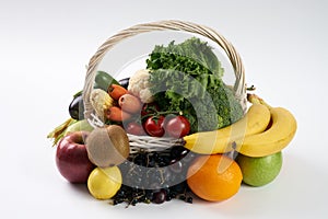 Close-up composition with raw vegetables and fruit in white wicker basket