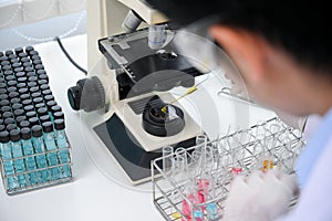 Close-up, Concentrated asian male scientist or chemist working in the labob, using microscope