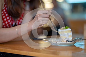 Close up concept hand of woman cut cake by fork in cafe or restaurant background