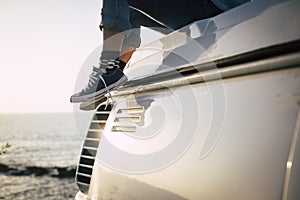 Close up concept of travel people enjoy the world with pair of blue sneakers and girl sit down on the roof of her van vehicle