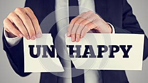 Close up Conceptual Businessman Tearing a White Paper with Unhappy - Happy Message Isolated on a Gray Background