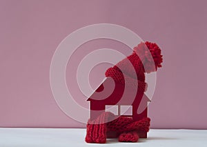 Close up conceptual miniature model house with red wool scarf hat on wooden background