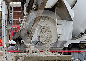 Close up of concrete flowing into excavator bucket from delivery vagon