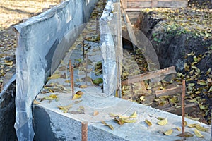 A close-up of the concrete footing in concrete forms with reinforcement bars as a concrete foundation for a fence