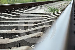 Close-up of concrete sleepers. In the foreground, a blurry, shiny railroad track. Railroad track Concept of railroading