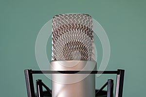 Close-up of a condenser studio microphone with a shock absorber on a blue background. The concept of high-quality professional