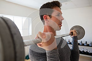 Close up of confident athelte lifting barbell at gym