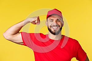 Close-up of confident and cheerful delivery guy showing how storng he is, can carry huge heavy packages, flex piceps and