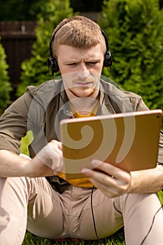 Close up confident man in headphones watching webinar, working on digital tablet