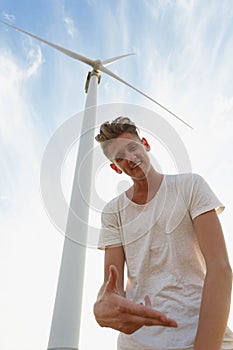 A sassy teenager on a blue sky background. Close-up of stylish hipster guy next to a windmill. Teenage years concept.