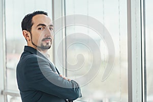 Close up of confident young businessman standing with his hands folded, looking at the camera, ready to hard work day.